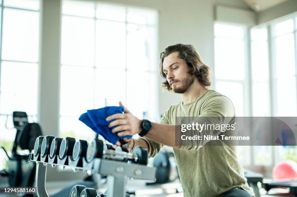 gym owner disinfecting exercise equipment by sterilizing solution in his gym.  protect member during gym opening after virus epidemic. - sports venue employee stock pictures, royalty-free photos & images