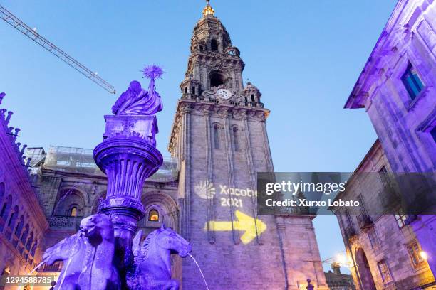 Night photo of the fountain of the horses in Platerias Square, and the clock tower or berenguela of the cathedral of Santiago. Illuminated with...