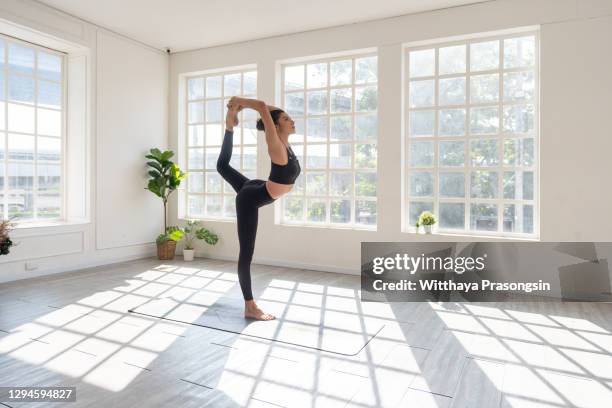 woman with arms raised yoga pose - yoga studio stock-fotos und bilder