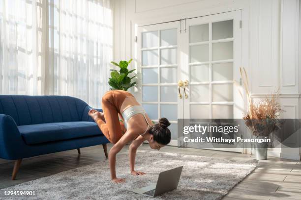 young sporty attractive woman practicing yoga, doing donkey kick exercise in front of her laptop - yogi stock pictures, royalty-free photos & images