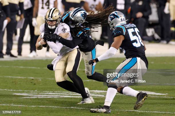 Quarterback Taysom Hill of the New Orleans Saints is tackled by safety Tre Boston of the Carolina Panthers during the second half of their game at...