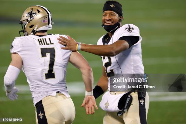 Quarterback Jameis Winston of the New Orleans Saints shares a smile as he greets teammate quarterback Taysom Hill during the second half of their...
