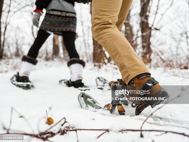 pareja mixta de raquetas de nieve en invierno - snowshoeing fotografías e imágenes de stock