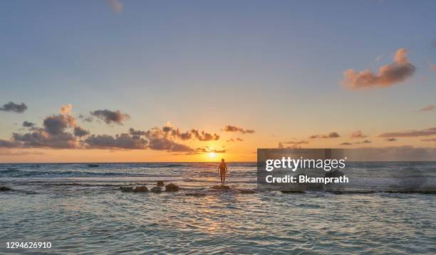 man walking on a sandbar during sunrise over the caribbean sea on cozumel island off the yucatan peninsula of mexico - cozumel stock pictures, royalty-free photos & images