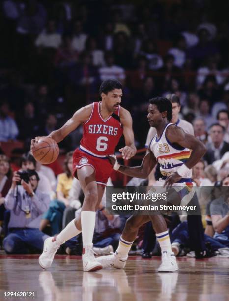 Julius Erving, Small Forward for the Philadelphia 76ers dribbles the basketball past Theodore Roosevelt Dunn, Small Forward of the Denver Nuggets...