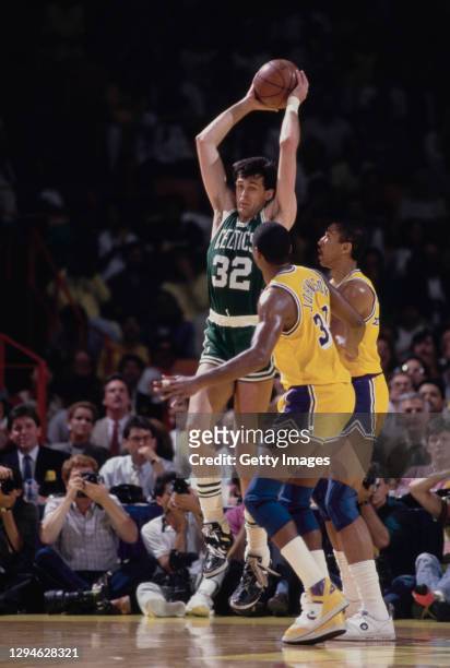 Kevin McHale, Power Forward for the Boston Celtics attempts a three point jump shot to the basket over Magic Johnson and Mychal Thompson of the Los...