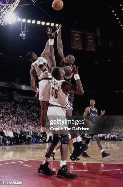 Shaquille O'Neal, Center for the Orlando Magic rolls a layup to the hoop as Dikembe Mutombo and LaPhonso Ellis of the Denver Nuggets attempts to...