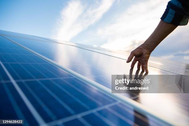 hände auf solarpanel, das energie erzeugt - solarstrom stock-fotos und bilder