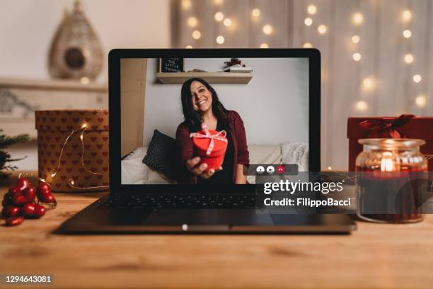 young woman giving a present for valentine's day during a videocall - parcel laptop stock pictures, royalty-free photos & images