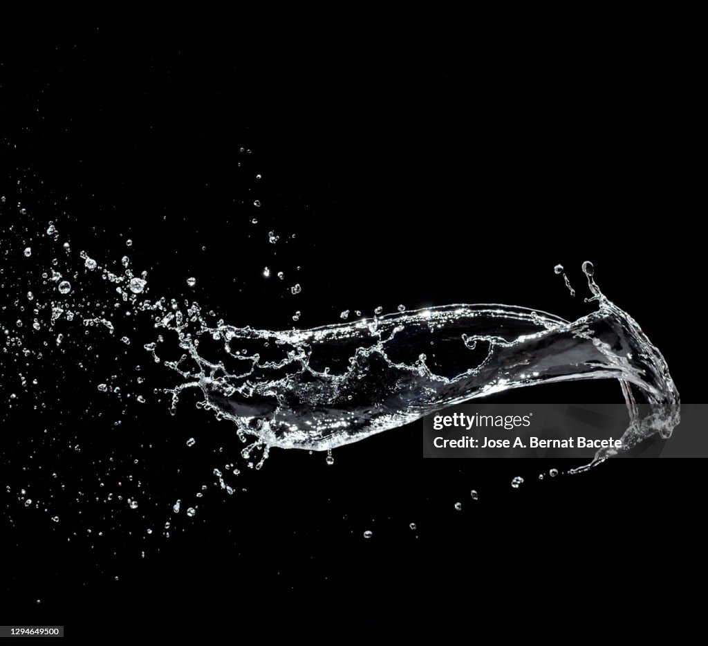 Splashes, jet and drops of water in motion suspended in the air on a black background.