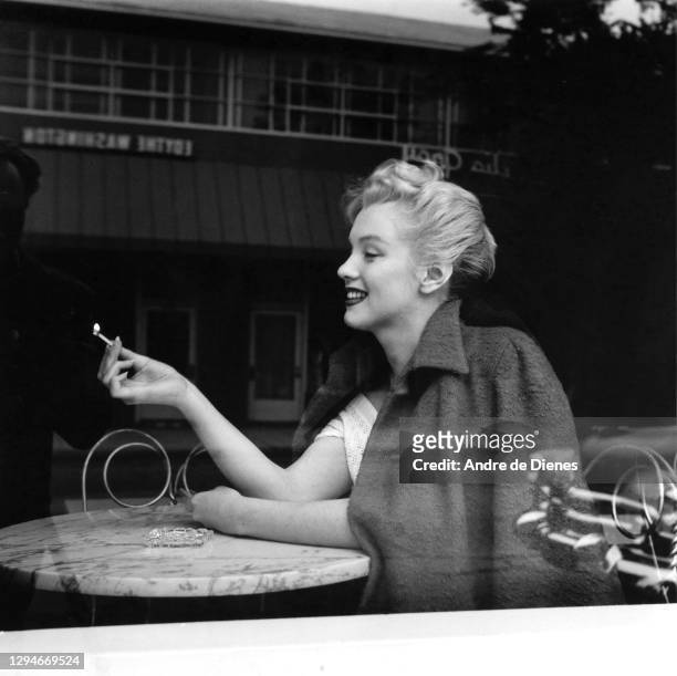 View of American actress and model Marilyn Monroe , a lit match in her hand, as she sits in an ice cream parlor, Hollywood, California, 1953.