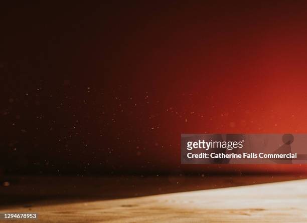background image of a pink wall behind a wooden table, half in shadow. dust floats, illuminated by sun. - focus on background stock pictures, royalty-free photos & images
