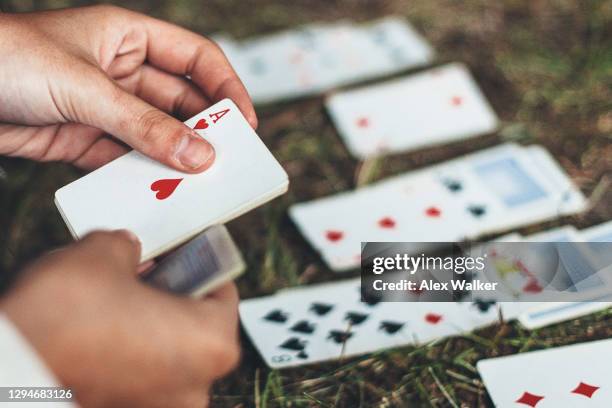 person playing game of cards on ground holding ace - solitaire card game stock pictures, royalty-free photos & images