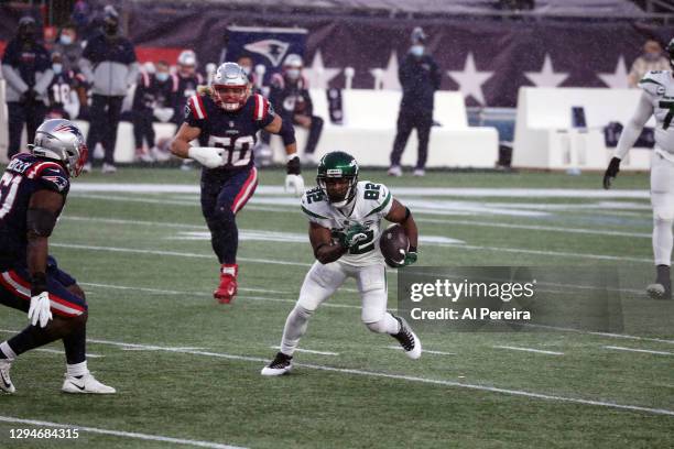 Jamison Crowder of the New York Jets carries the ball in the snow against the New England Patriots at Gillette Stadium on January 3, 2021 in...