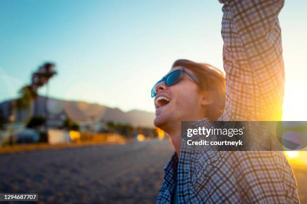 man alone dancing and celebrating on the beach at sunrise/sunset. - lens flare young people dancing on beach stock pictures, royalty-free photos & images