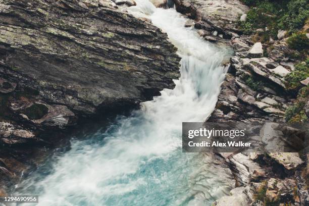 fast flowing river running through rocks in mountain pass - wildwasser fluss stock-fotos und bilder