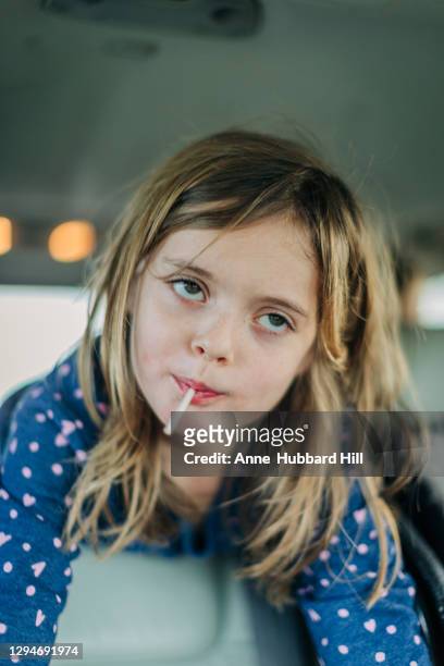 young girl in back of car with lollipop looking up and away - ぎょろ目 ストックフォトと画像