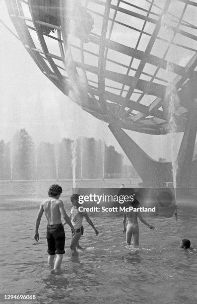 View of a small group of adolescent children wading in the fountain in front of the Unisphere in Flushing Meadows Park, in the Corona neighborhood,...