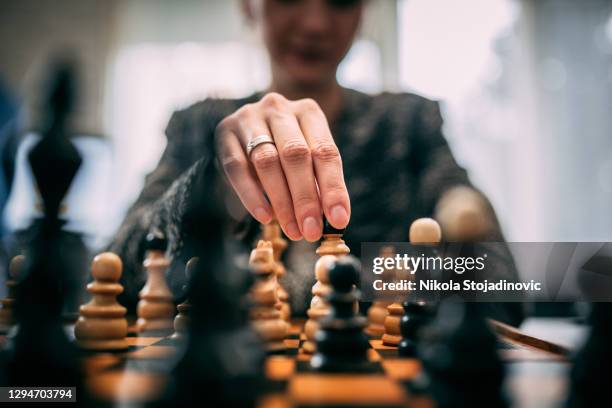 mujer jugando ajedrez - ajedrez fotografías e imágenes de stock