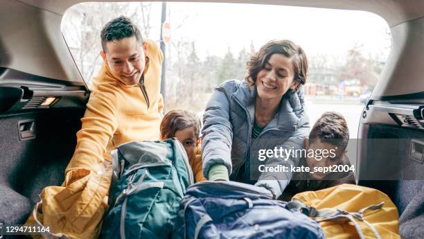 famiglia che carica un bagagliaio prima del viaggio - winter car foto e immagini stock