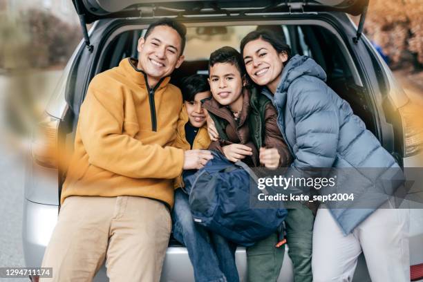 family  with two parents and two kids posing near car and looking to camera - winter road trip stock pictures, royalty-free photos & images