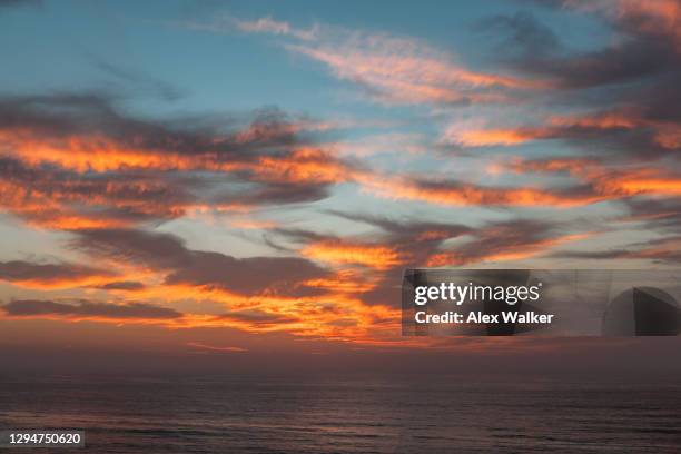 orange clouds at sunset over open ocean - goldene stunde stock-fotos und bilder