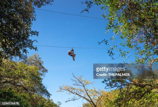 ten on a zip line in costa rica against blue sky - ziplining stock pictures, royalty-free photos & images