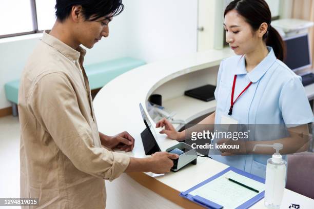 a man paying at a hospital using a smartphone - paying doctor stock pictures, royalty-free photos & images