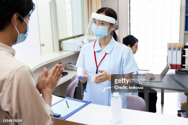 病院の受付で消毒する男性 - face shield ストックフォトと画像