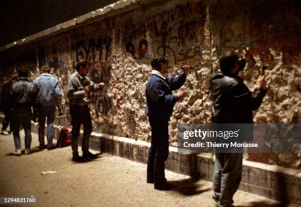 People with a chisel and sledgehammer participate in the destruction of the Berlin Wall near by the Brandenburg Gate, as they celebrate the first New...