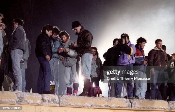 Revelers at the Brandenburg Gate stand on top of a remnant of the Berlin Wall, as they celebrate the first New Year in a unified Berlin since World...