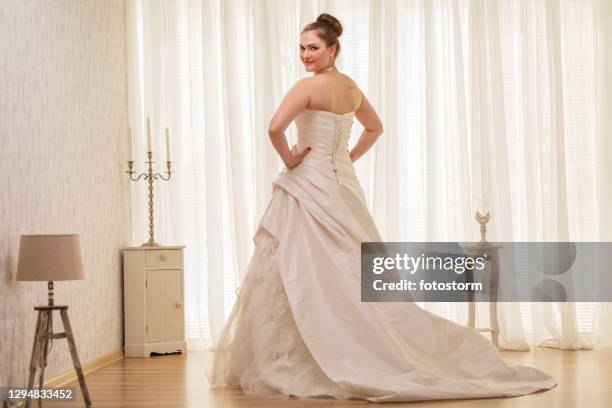 beautiful young bride looking at camera over the shoulder - backless dress stock pictures, royalty-free photos & images