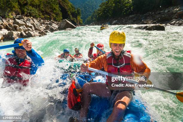 rafters get splashed as they go through some big rapids on the karnali river in nepal - rafting sulle rapide foto e immagini stock