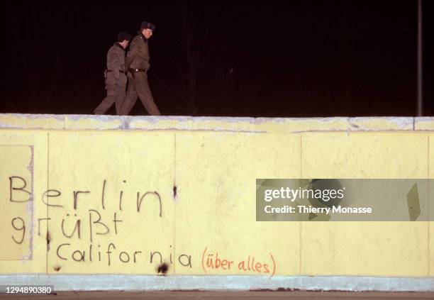 East Deutsche Volkspolizei walks on the Berlin wall during the New-Year Eve. On the wall people wrotes: "Berlin greets California " on December 31,...