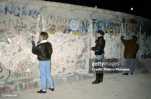 People with a chisel and sledgehammer participate in the destruction of the Berlin Wall near by the Brandenburg Gate, as they celebrate the first New...