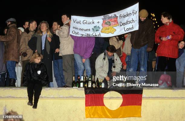 Reunited Germans celebrate New Year's Eve atop the Berlin Wall two months after the border between the divided city was opened on December 31, 1989...