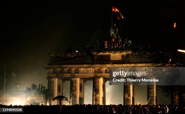 Revelers at the Brandenburg Gate stand on top of a remnant of the Berlin Wall, as they celebrate the first New Year in a unified Berlin since World...