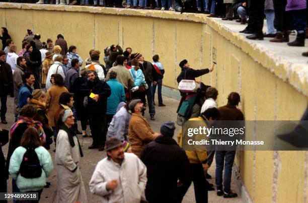 Revelers at the Brandenburg Gate stand on top of a remnant of the Berlin Wall, as they celebrate the first New Year in a unified Berlin since World...