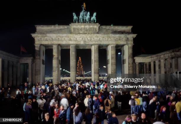 Revelers at the Brandenburg Gate stand on top of a remnant of the Berlin Wall, as they celebrate the first New Year in a unified Berlin since World...