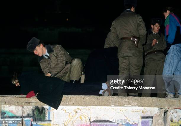 East Deutsche Volkspolizei helps a woman to climb on the Berlin wall during the New-Year Eve on December 31, 1989 in Berlin, Germany.