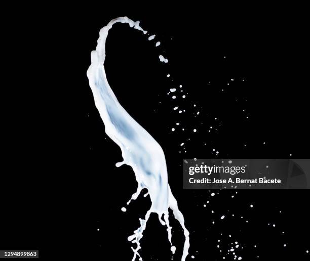 splashes, jet and drops of milk in motion suspended in the air on a black background. - milk wave stock pictures, royalty-free photos & images