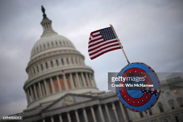Supporters of U.S. President Donald Trump fly a U.S. Flag with a symbol from the group QAnon as they gather outside the U.S. Capitol January 06, 2021...