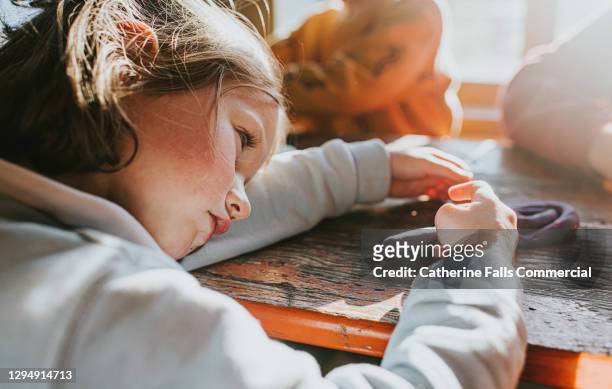 a young girl in preschool puts her head down on the desk and pouts - low self esteem stock pictures, royalty-free photos & images