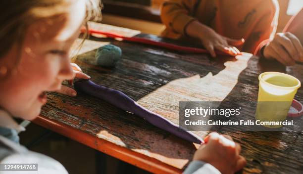 a young girl plays with purple plasticine - child's play clay stock pictures, royalty-free photos & images