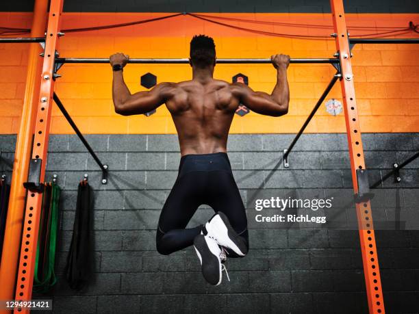 hombre haciendo ejercicio en un gimnasio haciendo pull-ups - flexión de brazos fotografías e imágenes de stock