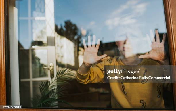 child pressing hands against a window and looks out - stuck indoors stock pictures, royalty-free photos & images