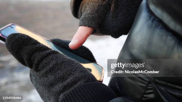 man playing an ar game on mobile phone during winter with cutoff gloves - white glove phone stock pictures, royalty-free photos & images