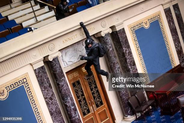 Protester is seen hanging from the balcony in the Senate Chamber on January 06, 2021 in Washington, DC. Congress held a joint session today to ratify...