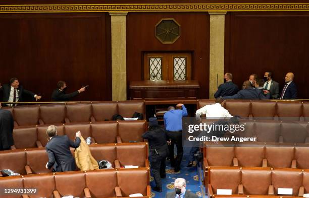 Capitol police officers point their guns at a door that was vandalized in the House Chamber during a joint session of Congress on January 06, 2021 in...