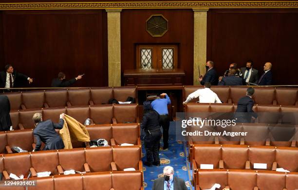 Capitol police officers point their guns at a door that was vandalized in the House Chamber during a joint session of Congress on January 06, 2021 in...